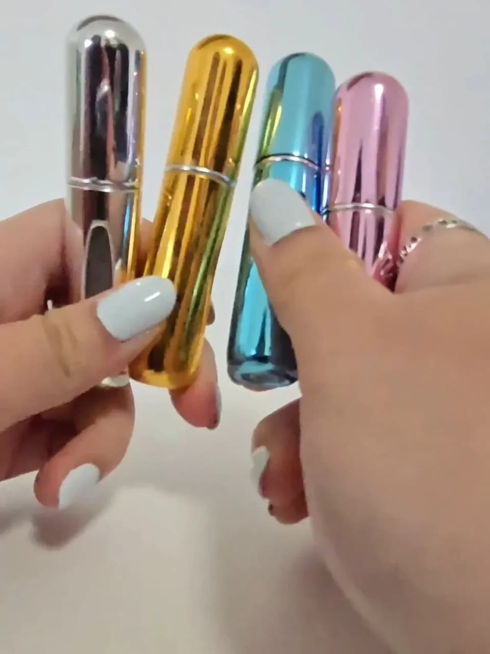 Atomiseur de parfum rechargeable miniature posé sur fond blanc
